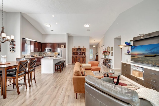 living area featuring plenty of natural light, light wood finished floors, and high vaulted ceiling