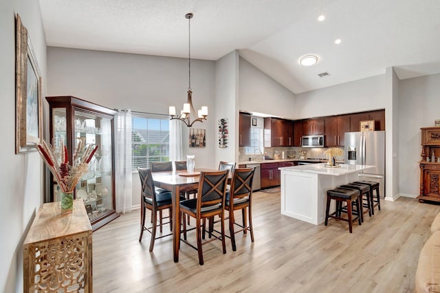 dining space featuring high vaulted ceiling, baseboards, a notable chandelier, light wood-style floors, and recessed lighting
