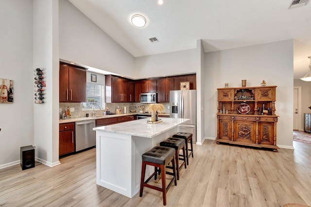 kitchen featuring a breakfast bar, stainless steel appliances, light wood-type flooring, and visible vents