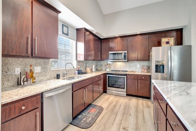 kitchen featuring a sink, appliances with stainless steel finishes, tasteful backsplash, and light wood-style floors