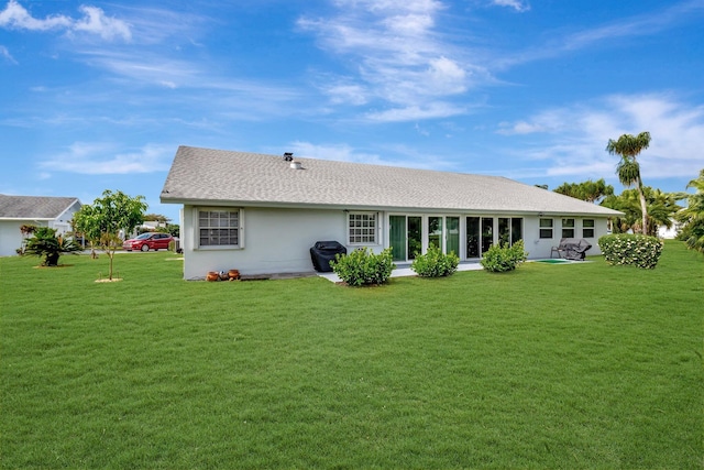 rear view of property with stucco siding and a yard