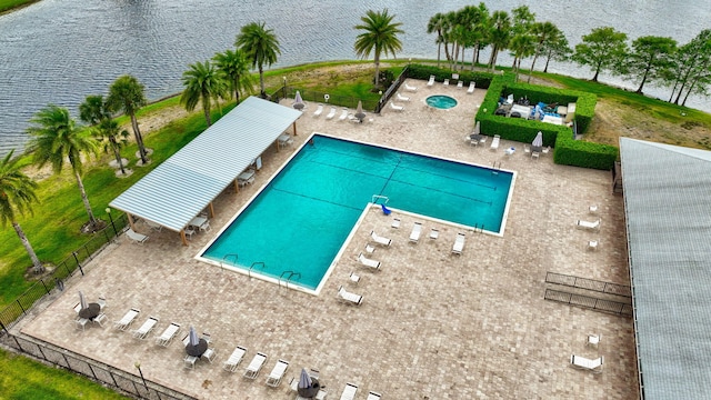 community pool with a water view and fence