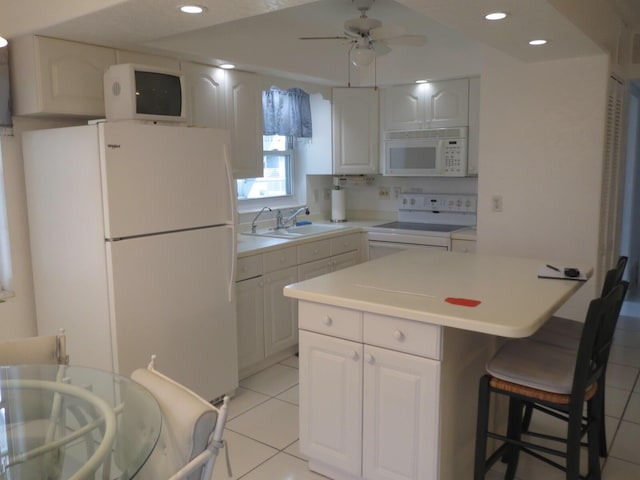 kitchen with white appliances, light tile patterned flooring, white cabinets, and a sink