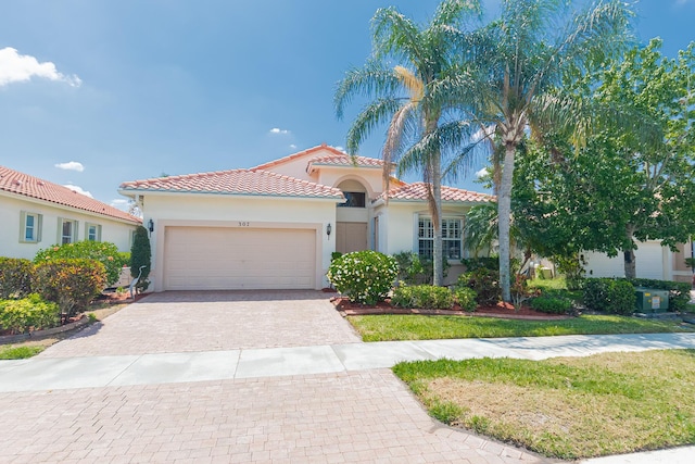 307 NW Clearview Ct, Port Saint Lucie, FL 34986 - mediterranean / spanish house featuring decorative driveway, an attached garage, stucco siding, and a tiled roof