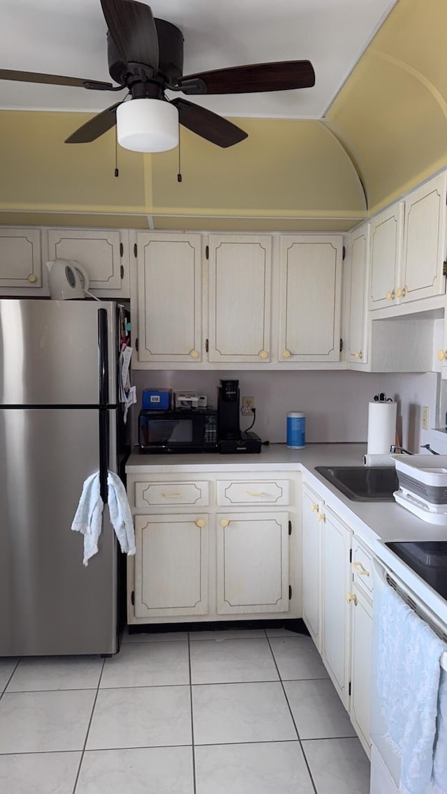 kitchen featuring freestanding refrigerator, light tile patterned floors, black microwave, white cabinets, and a ceiling fan