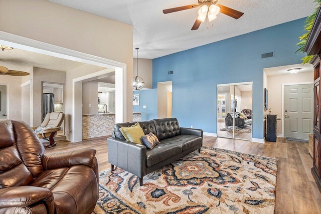 648 Deer Creek Edgewater Dr, Deerfield Beach, FL 33442 - living area featuring a textured ceiling, visible vents, wood finished floors, and ceiling fan with notable chandelier