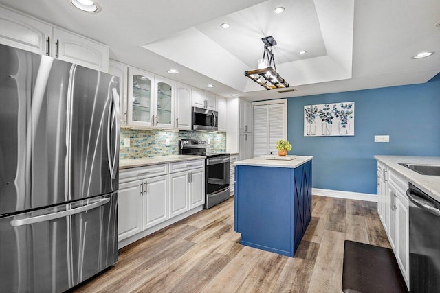 648 Deer Creek Edgewater Dr, Deerfield Beach, FL 33442 - kitchen with a center island, stainless steel appliances, baseboards, white cabinets, and a tray ceiling