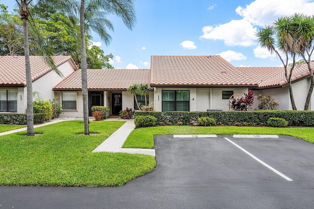 648 Deer Creek Edgewater Dr, Deerfield Beach, FL 33442 - view of front facade with stucco siding, a front lawn, a tile roof, and uncovered parking