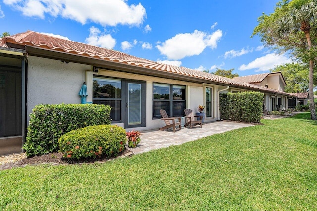 648 Deer Creek Edgewater Dr, Deerfield Beach, FL 33442 - rear view of property featuring a lawn, a patio area, stucco siding, and a tiled roof