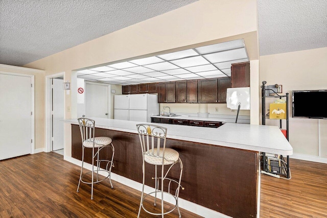 648 Deer Creek Edgewater Dr, Deerfield Beach, FL 33442 - kitchen with dark wood finished floors, dark brown cabinets, light countertops, freestanding refrigerator, and a breakfast bar