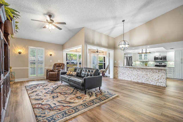 648 Deer Creek Edgewater Dr, Deerfield Beach, FL 33442 - living area featuring a textured ceiling, light wood-style flooring, and ceiling fan with notable chandelier