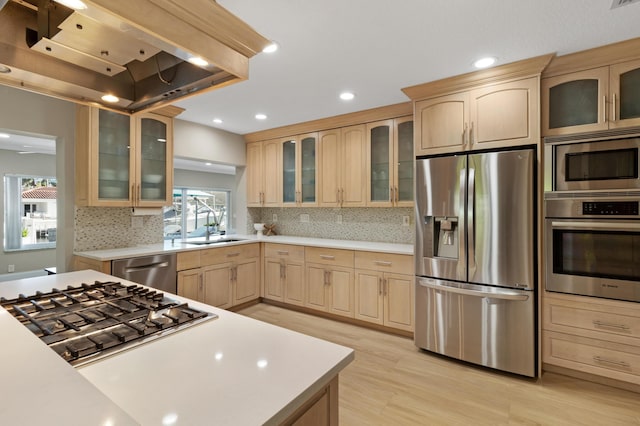 kitchen featuring stainless steel appliances, light brown cabinets, light countertops, light wood-type flooring, and a sink