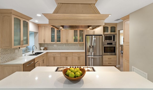 kitchen featuring stainless steel appliances, a sink, light brown cabinets, island range hood, and backsplash