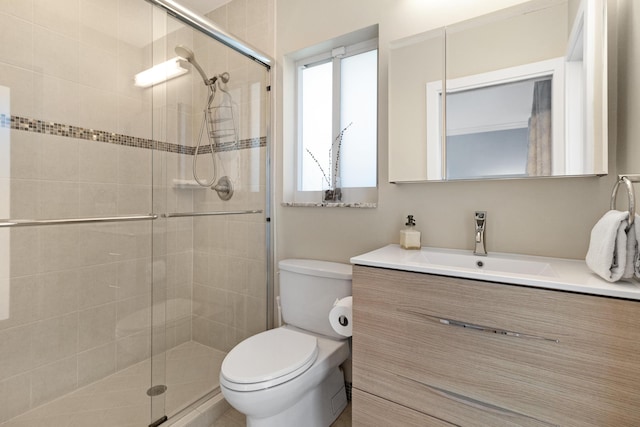 bathroom featuring a shower stall, toilet, and vanity