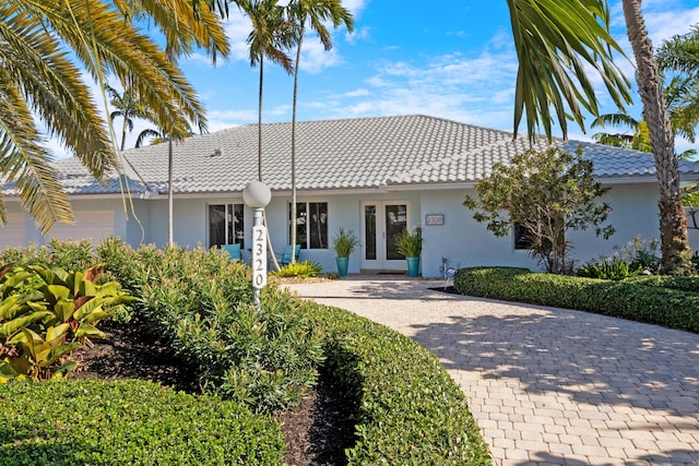 ranch-style home with stucco siding, a tiled roof, and french doors