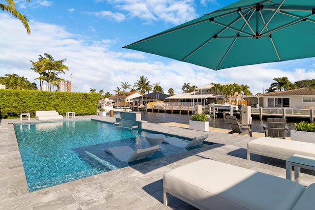 outdoor pool with a patio, a water view, and a boat dock