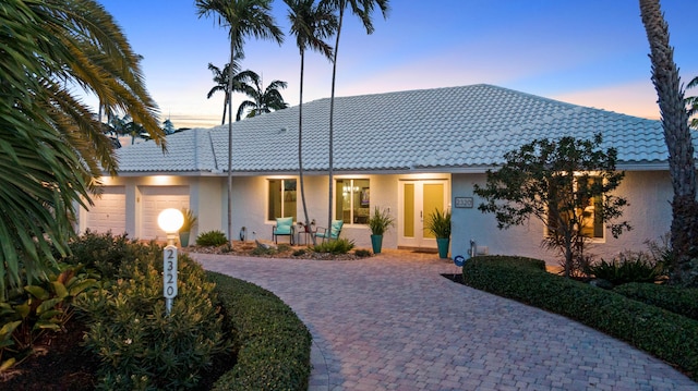 view of front facade with a tile roof, an attached garage, and stucco siding