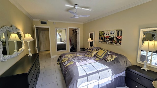 bedroom featuring light tile patterned floors, a walk in closet, ornamental molding, and visible vents