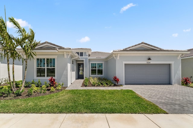 10241 SW Carnelian St, Port Saint Lucie, FL 34987 - view of front facade featuring an attached garage, a front lawn, a tile roof, stucco siding, and decorative driveway