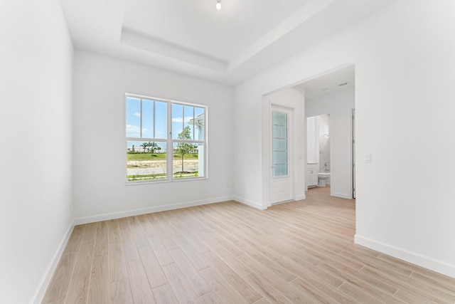 10241 SW Carnelian St, Port Saint Lucie, FL 34987 - empty room with baseboards, a tray ceiling, and light wood-style flooring