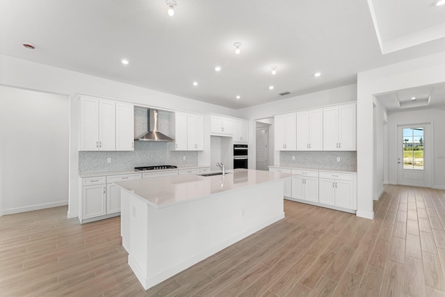 10241 SW Carnelian St, Port Saint Lucie, FL 34987 - kitchen with a sink, light wood-style flooring, wall chimney exhaust hood, a large island with sink, and black stovetop