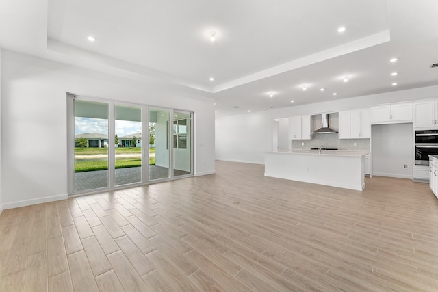 10241 SW Carnelian St, Port Saint Lucie, FL 34987 - unfurnished living room featuring visible vents, baseboards, recessed lighting, light wood-type flooring, and a tray ceiling