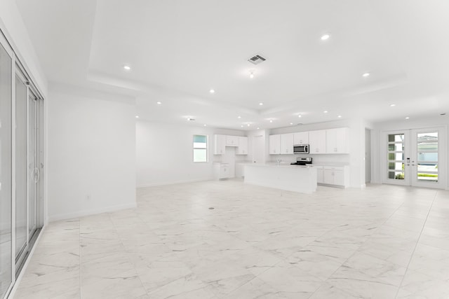 10128 SW Carnelian St, Port Saint Lucie, FL 34987 - unfurnished living room with french doors, recessed lighting, baseboards, a tray ceiling, and visible vents