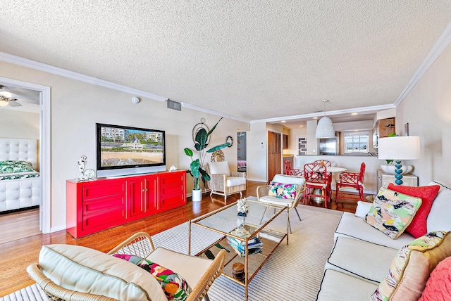 living area featuring a textured ceiling, baseboards, visible vents, crown molding, and wood finished floors