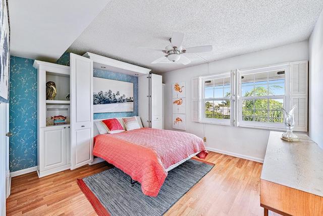 bedroom featuring wallpapered walls, light wood-type flooring, and baseboards