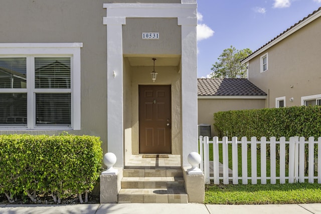10531 NW 57th St, Coral Springs, FL 33076 - view of exterior entry featuring fence, stucco siding, and a tile roof