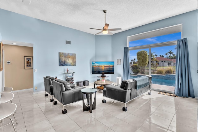 living room featuring a ceiling fan, baseboards, visible vents, and a textured ceiling