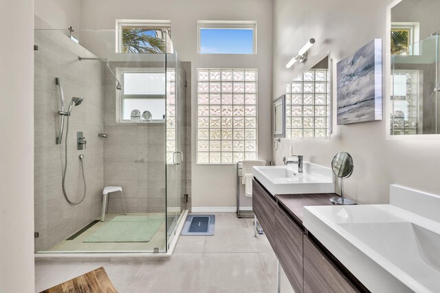 bathroom with double vanity, tile patterned floors, a stall shower, and a sink