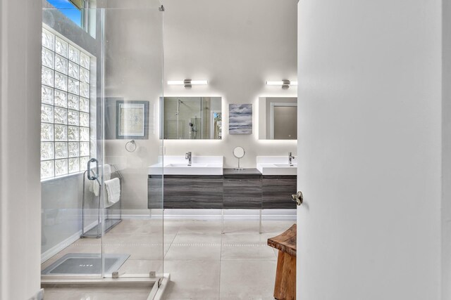 bathroom with double vanity, tile patterned floors, a stall shower, and a sink