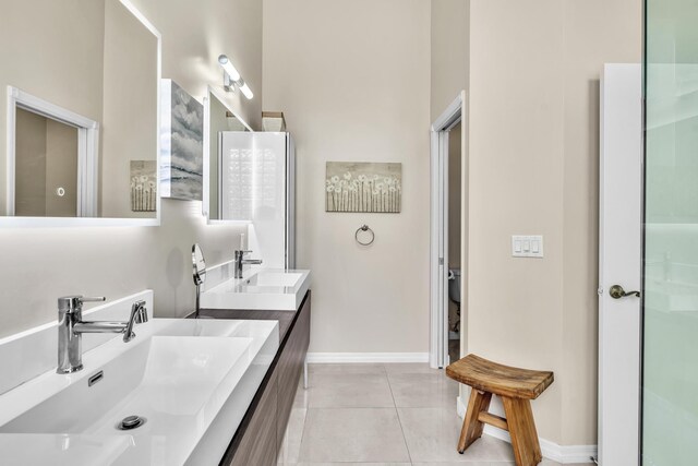 bathroom featuring tile patterned flooring, a sink, baseboards, and double vanity