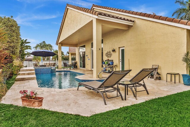 view of pool with a patio, fence, and a pool with connected hot tub
