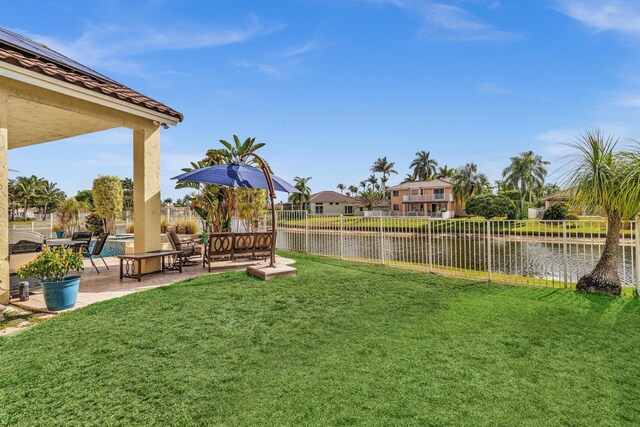 view of yard with a fenced backyard, a patio, and a water view