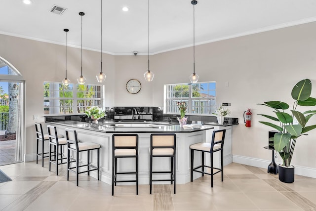 19323 King Palm Ct, Boca Raton, FL 33498 - kitchen featuring dark countertops, crown molding, a kitchen bar, baseboards, and decorative light fixtures