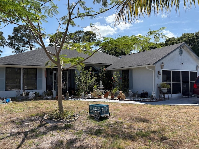 ranch-style house featuring a shingled roof, stucco siding, a patio area, and a front yard