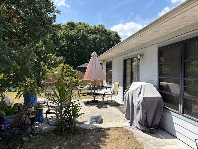 view of patio with fence, outdoor dining area, and a grill