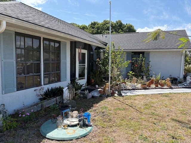 exterior space featuring a shingled roof and a front yard