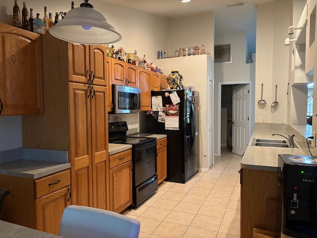 kitchen featuring a sink, light tile patterned flooring, black appliances, and brown cabinets