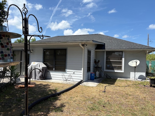 back of property featuring roof with shingles and a yard