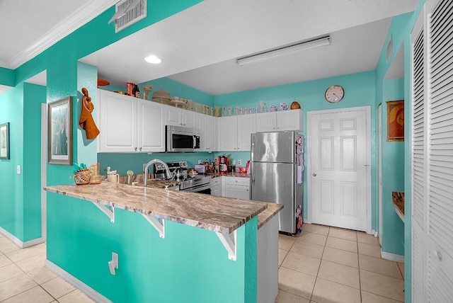 kitchen featuring light tile patterned floors, stainless steel appliances, a peninsula, and visible vents