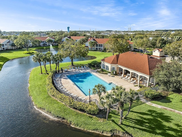community pool with a water view, a patio area, and a yard