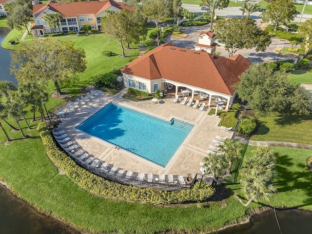 pool featuring a patio, a water view, and a yard