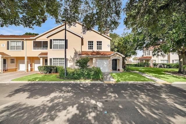 view of front of home with stucco siding, an attached garage, driveway, and a front yard