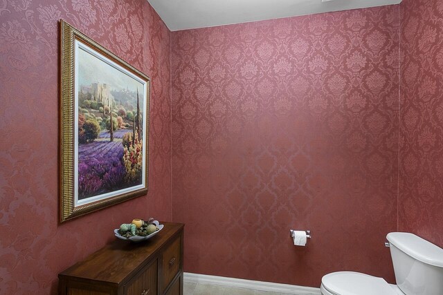 half bathroom featuring baseboards and toilet