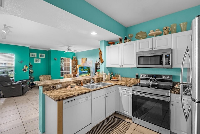 kitchen with appliances with stainless steel finishes, a sink, a peninsula, open floor plan, and light tile patterned flooring