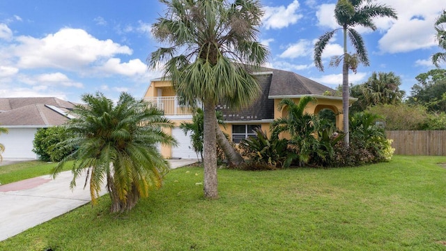 2650 SW Acco Rd, Port Saint Lucie, FL 34953 - view of front of house with fence, a balcony, a front lawn, concrete driveway, and stucco siding