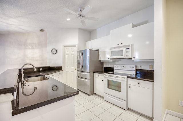 606 SW Treasure Cv, Port Saint Lucie, FL 34986 - kitchen with white appliances, a sink, dark countertops, white cabinets, and light tile patterned floors